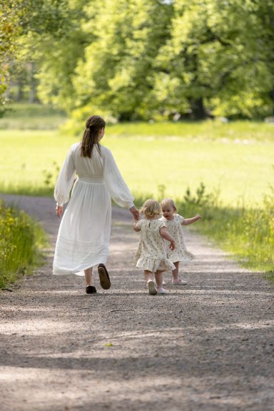 Mamma går längs somrig grusväg med barn i handen i foto av dokumentär storytelling stil av Anna Esmelöv, Åtvidaberg