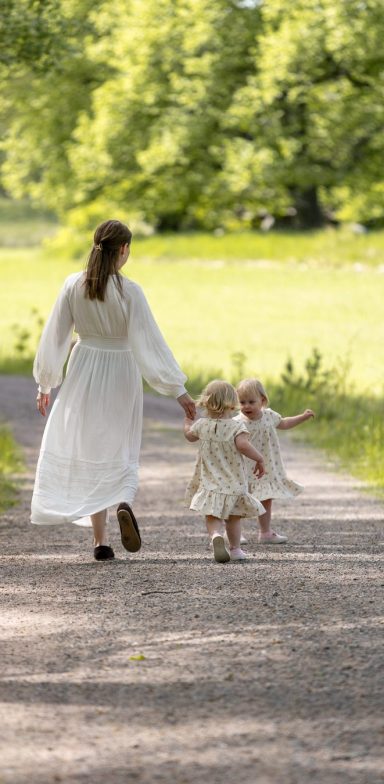 Mamma går längs somrig grusväg med barn i handen i foto av dokumentär storytelling stil av Anna Esmelöv, Åtvidaberg