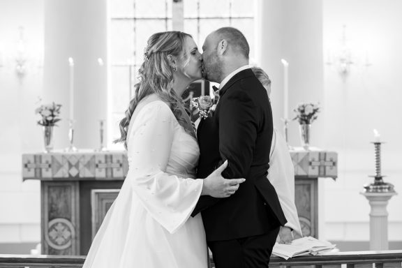 Första kyssen under vigsel i Kuddby kyrka, Östergötland, svartvitt foto av bröllopsfotograf Anna Esmelöv